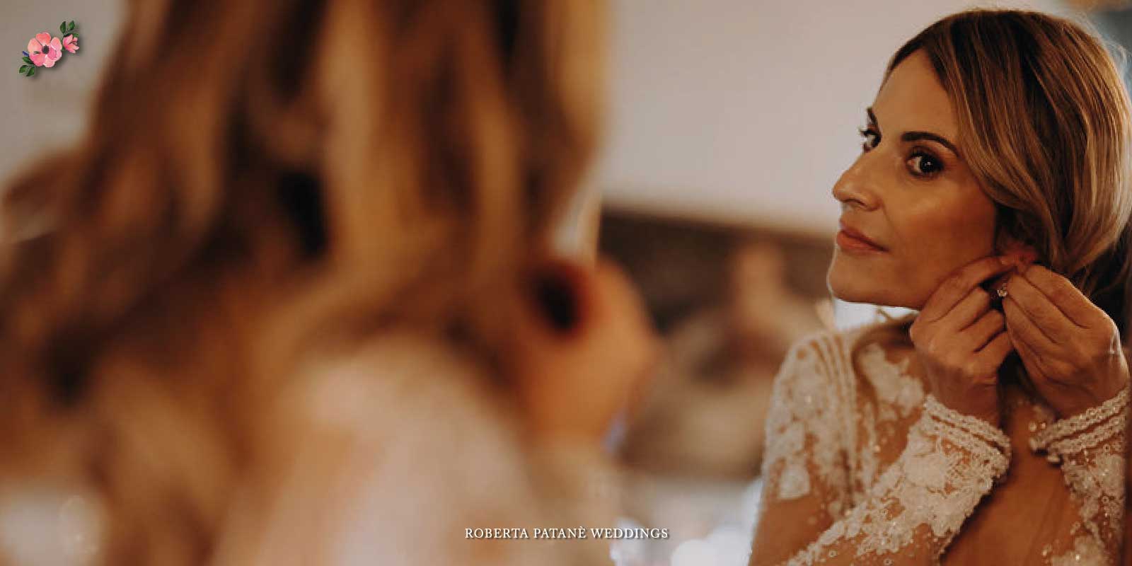 Sposa che sistema l'orecchino allo specchio mentre valuta gli accessori