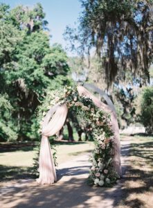 Allestimento cerimonia diurno con arco di tessuti e fiori