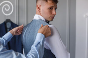 Sposo misura l'abito indossando il gilet sopra la camicia bianca