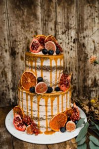 Torta nuziale al caramello e cacao ispirata all'autunno con arance, melagrane, uva e fichi