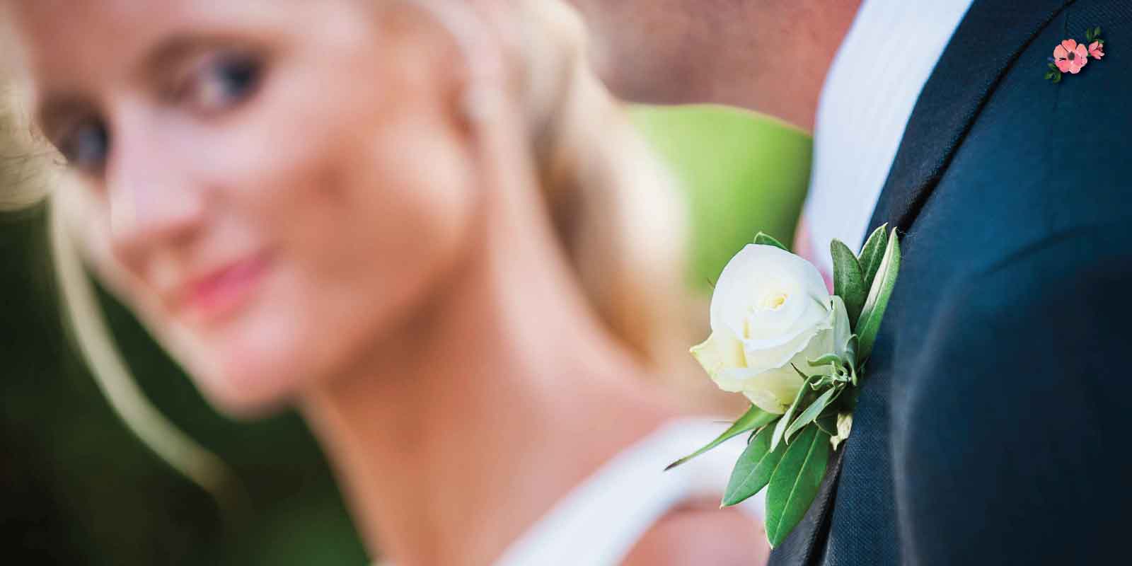 Accessori-floreali Boutonnière dello sposo in primo piano sotto il dolce sguardo della sposa