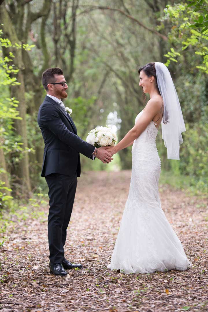 Matrimonio-total-white-a-cura-di-Roberta-Patane Sposi che si tengono per mano nel bosco